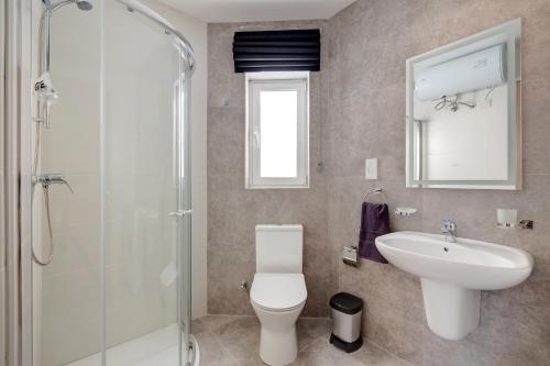 a bathroom with a toilet and a sink and a shower at Valley's Edge Apartments in San Ġwann
