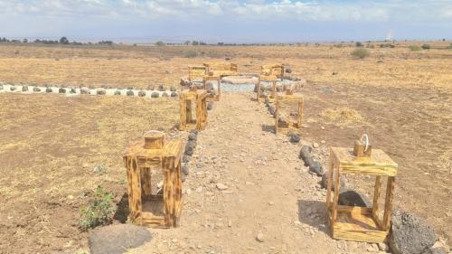 a row of wooden tables in the middle of a field at Amanya Star Bed Amboseli in Amboseli