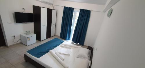 sypialnia z białym łóżkiem i niebieskimi zasłonami w obiekcie Vila Bella 2M w mieście Costinesti