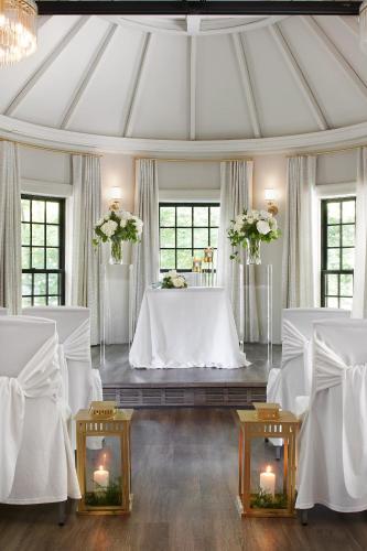 a room with white tables and chairs and flowers at The Glenerin Inn in Mississauga