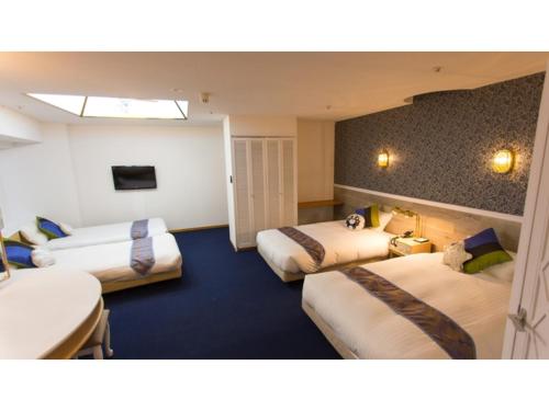 a hotel room with three beds and a tv at Hotel AreaOne Sakaiminato Marina - Vacation STAY 81788v in Sakaiminato