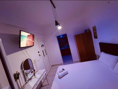 een slaapkamer met een wit bed en een tv aan de muur bij Blue Hotel boutique in Selínia