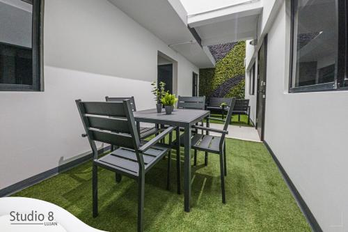 a table and chairs on a patio with grass at Studio8 Lujan Apartament 1 in San José