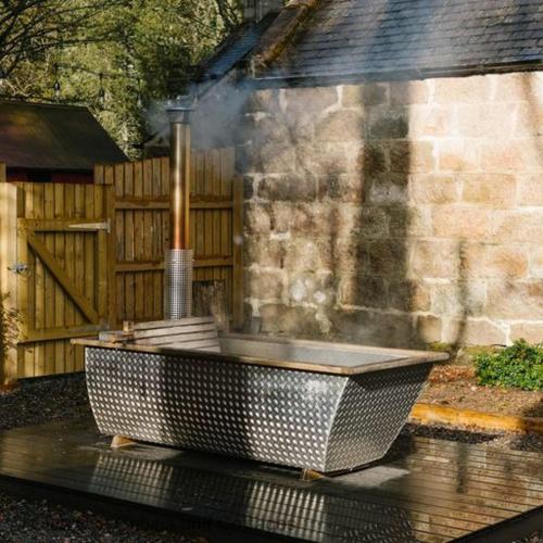 a bath tub sitting in the middle of a yard at The Bothy in Banchory