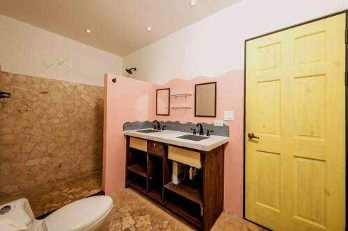 Un baño con lavabo e inodoro y una puerta amarilla. en Casita Mar Y Posa, en Potrero
