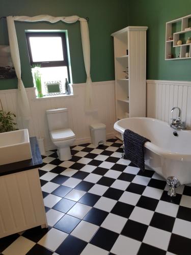 ein Badezimmer mit schwarz-weiß kariertem Boden in der Unterkunft Atlantic Coast Holiday Home in Mountcharles
