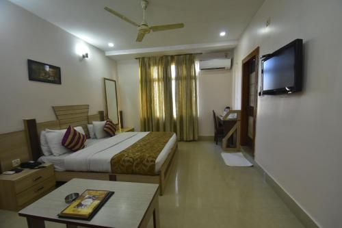 a hotel room with a bed and a flat screen tv at Hotel Royal Highness in Tinsukia