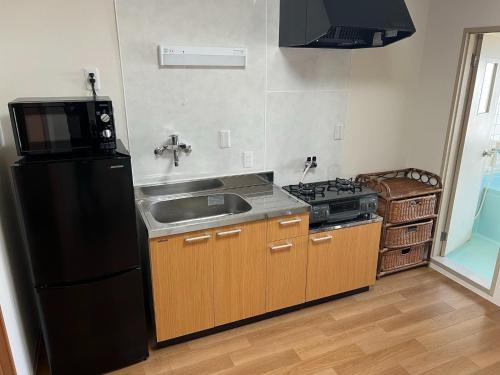 een keuken met een wastafel en een zwarte koelkast bij Wakatake Building Room 453 - Vacation STAY 53947v in Oita