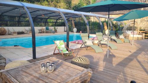 una terraza con sillas, una sombrilla y una piscina en Manoir des Pélies, en Conques