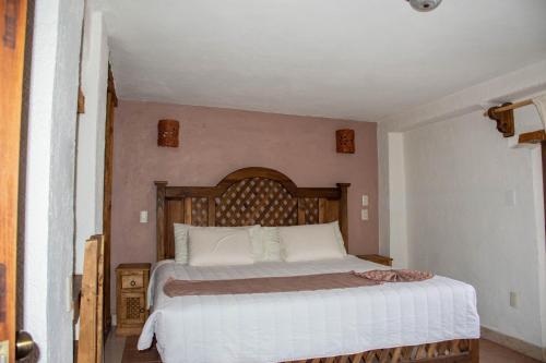 a bedroom with a large bed with a wooden headboard at Hotel Real del Carmen - Ideal para familias y parejas in San Cristóbal de Las Casas