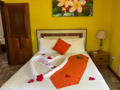 a bed with orange and white sheets and flowers on it at Chloe's Cottage Self-Catering in La Digue
