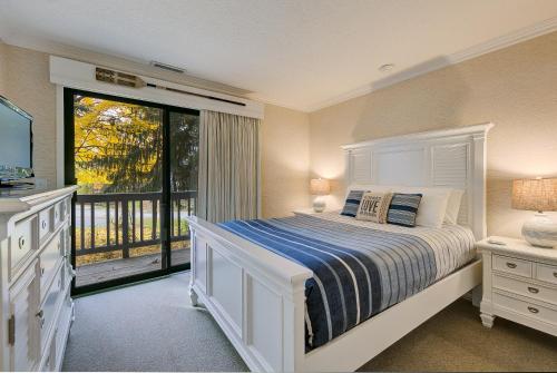 um quarto com uma cama e uma grande janela em Gorgeous Grand Traverse Bay Beach Front Condo em Traverse City