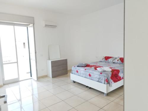 a white bedroom with a bed and a window at Luan's House in Pozzallo