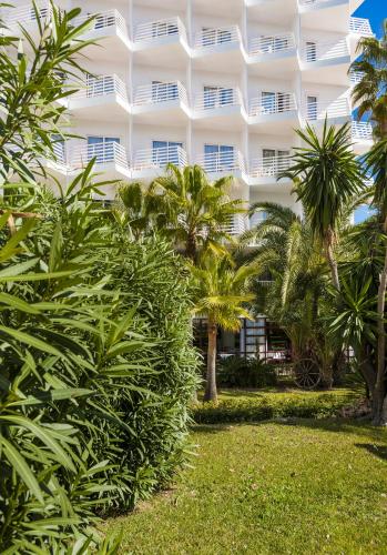 a white building with palm trees in front of it at Globales Palmanova in Palmanova