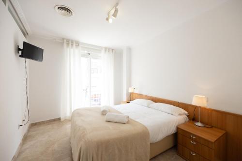 Habitación blanca con cama y TV en Apartamentos Turísticos Alba, en Cartagena