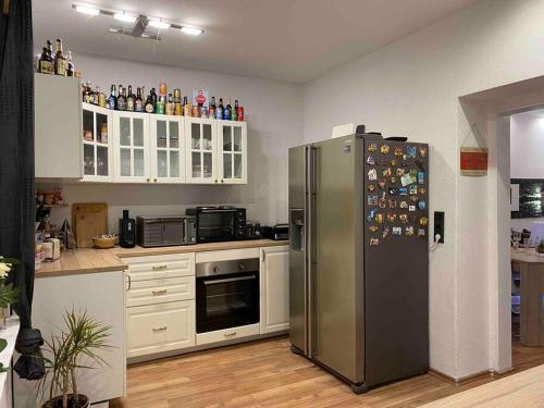 La cuisine est équipée d'un réfrigérateur en acier inoxydable et de placards blancs. dans l'établissement Modern Apartment near RedBull Circuit, à Zeltweg