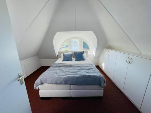 a small bedroom with a bed with a window at Vakantiehuis aan het water in Friesland in De Rijlst