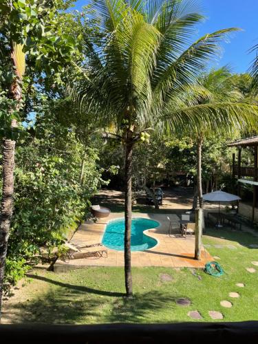 a palm tree next to a swimming pool at Maui Suítes e Chalés in Arraial d'Ajuda
