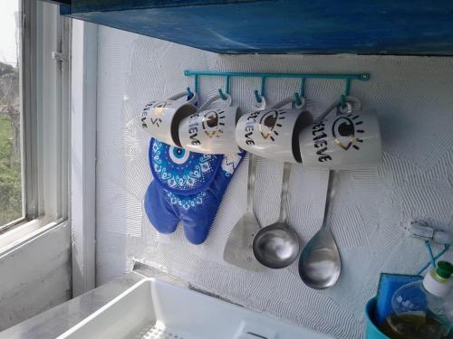 a bunch of cups and spoons hanging on a wall at Stefanos' Art House in Halikounas