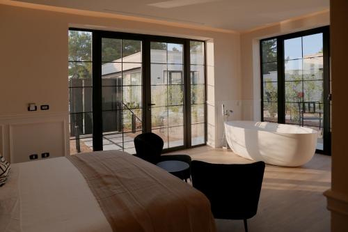 ein Schlafzimmer mit einer Badewanne und einem großen Fenster in der Unterkunft Salento Winery Lodge in San Pietro in Bevagna
