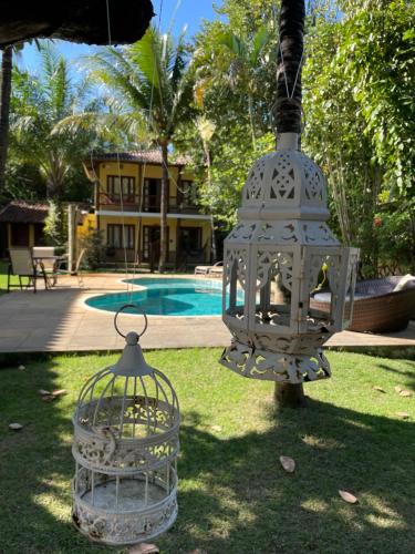 a bird cage hanging from a tree next to a house at Maui Suítes e Chalés in Arraial d'Ajuda