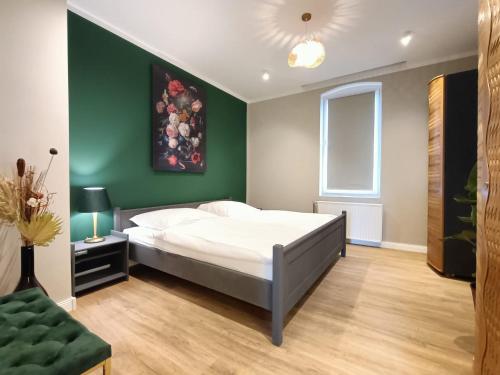 a bedroom with a white bed and a green wall at Ferienwohnung Coburg, familienfreundlich und stilvoll in Coburg