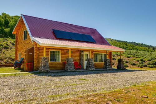 a log cabin with a solar roof on a gravel road at Mountain Cabin in Wyoming Range Scenic and Remote! in Kemmerer
