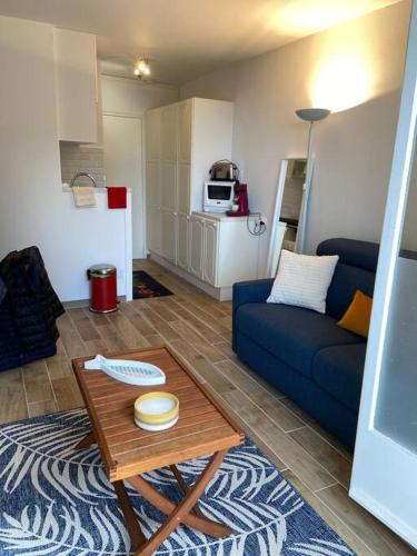 un salon avec un canapé bleu et une table dans l'établissement JOLI STUDIO VUE MER , plage au bout de la rue !, à Villers-sur-Mer