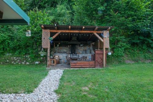 a barbecue under a wooden structure in a yard at ECO cabin Plivsko jezero Jajce in Jajce