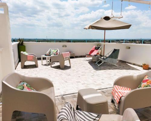 eine Terrasse mit Stühlen und einem Sonnenschirm auf dem Dach in der Unterkunft Domus Santi Medici Affittacamere in Massafra