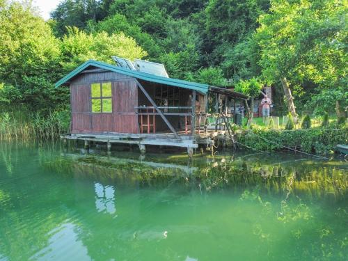ein Haus an einem Fluss mit einer Reflexion im Wasser in der Unterkunft ECO cabin Plivsko jezero Jajce in Jajce