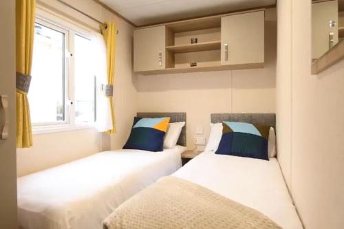 two beds in a small room with a window at Rohannah static Caravan Fantastic Family and Friends Holiday in East Mersea