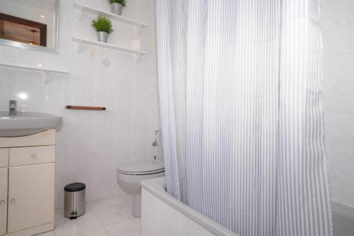 a white bathroom with a shower curtain and a toilet at 10A02 Precioso apartamento Pravia in Pravia