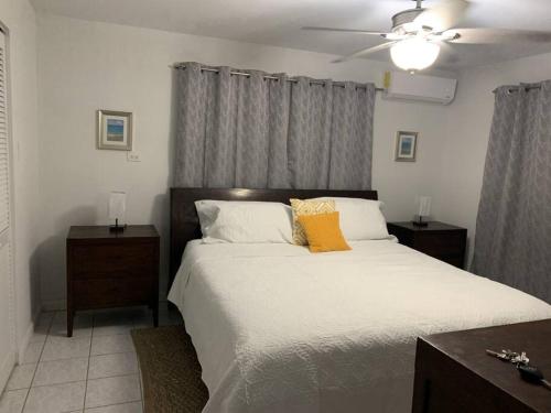 a bedroom with a large white bed with a yellow pillow at The Diver's Inn Grand Cayman in George Town