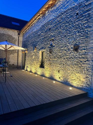 a brick wall with an umbrella on a wooden deck at Gite confortable au milieu des prés - La ferme de Montigny in Neauphe-sur-Dives