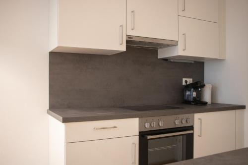 a kitchen with white cabinets and a stove top oven at Flat2go modern apartments - Harmony of city and nature in Vienna