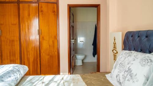 a bedroom with a bed and a bathroom with a toilet at The Terrace Villa in Kampala