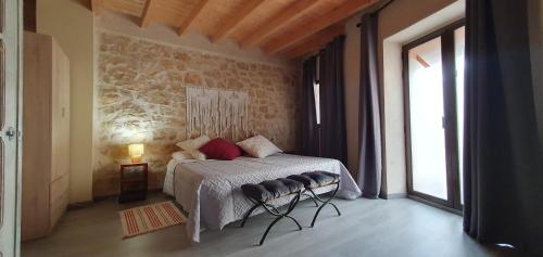 a bedroom with a bed and a stone wall at APARTAMENTS LA DONZELLA in Bot