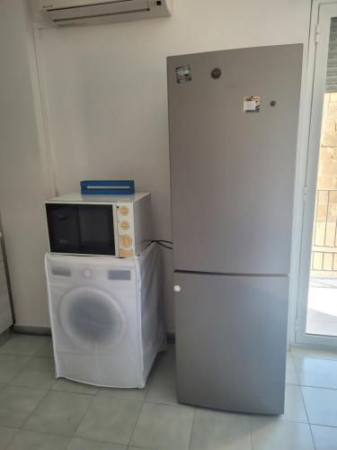 eine Küche mit einer Mikrowelle, einer Waschmaschine und einem Kühlschrank in der Unterkunft Bilocale Lungomare Carini in Carini