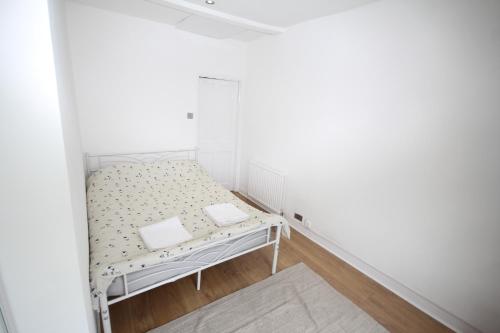 a small white room with a bed in the corner at Brunswick Cottage in Reading