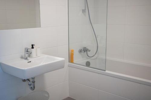 a white bathroom with a sink and a shower at Flat2go modern apartments - Harmony of city and nature in Vienna