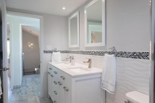 bagno bianco con lavandino e specchio di Beach Living at Villas Pappagallo BLES a West Bay