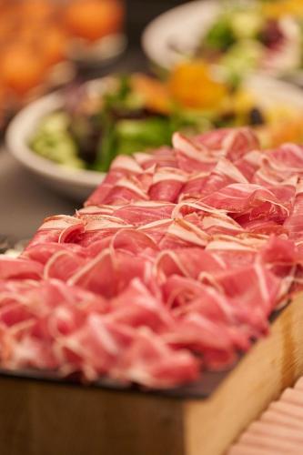 a pile of meat on a table with plates of food at Hotel Regina in Madrid