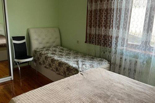 Cette chambre dispose de deux lits, d'une chaise et d'une fenêtre. dans l'établissement House in beautiful Kutaisi, à Koutaïssi