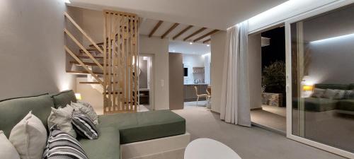 a living room with a green couch and a staircase at Les Maisonettes in Kokkari