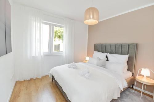 a white bedroom with a large bed and a window at Moderne & Elegante Terrassenwohnung - Wifi - TV in Bielefeld