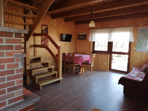 a dining room with a table and a staircase in a cabin at Domek Czerwony Kapturek in Płocice