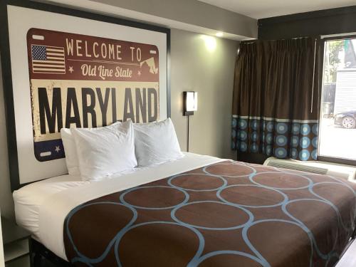 a bed in a hotel room with a welcome to out of the statemaury at Super 8 by Wyndham Baltimore Northwest in Baltimore