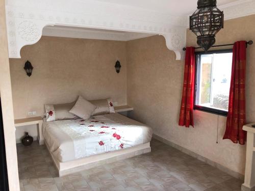 een slaapkamer met een bed en een raam met rode gordijnen bij Dar Tiziri Amizmiz in Marrakesh