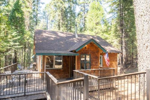 uma cabana de madeira com um deque na floresta em The Cedar Loft - Pet and Family Friendly - BBQ/Pool/Fire Pit em Camp Connell